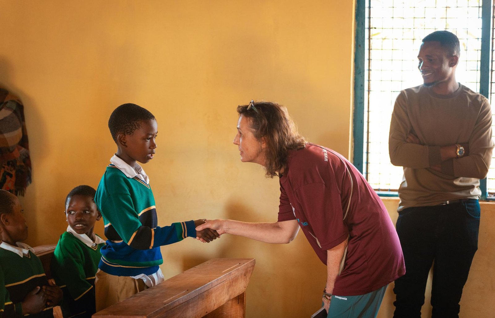 A volunteer greeting a pupil in class